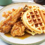 Homemade Chicken and Waffles 7 Homemade chicken and waffles topped with syrup and butter on a rustic wooden table