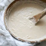 How To Make Sourdough Starter 5 Close-up of bubbly sourdough starter in a glass jar, showcasing a healthy fermentation process with flour and water mix.