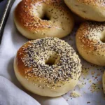 Sourdough Discard Bagels 8 Golden-brown sourdough discard bagels with a chewy texture and slightly tangy flavor, sprinkled with sesame seeds and poppy seeds.