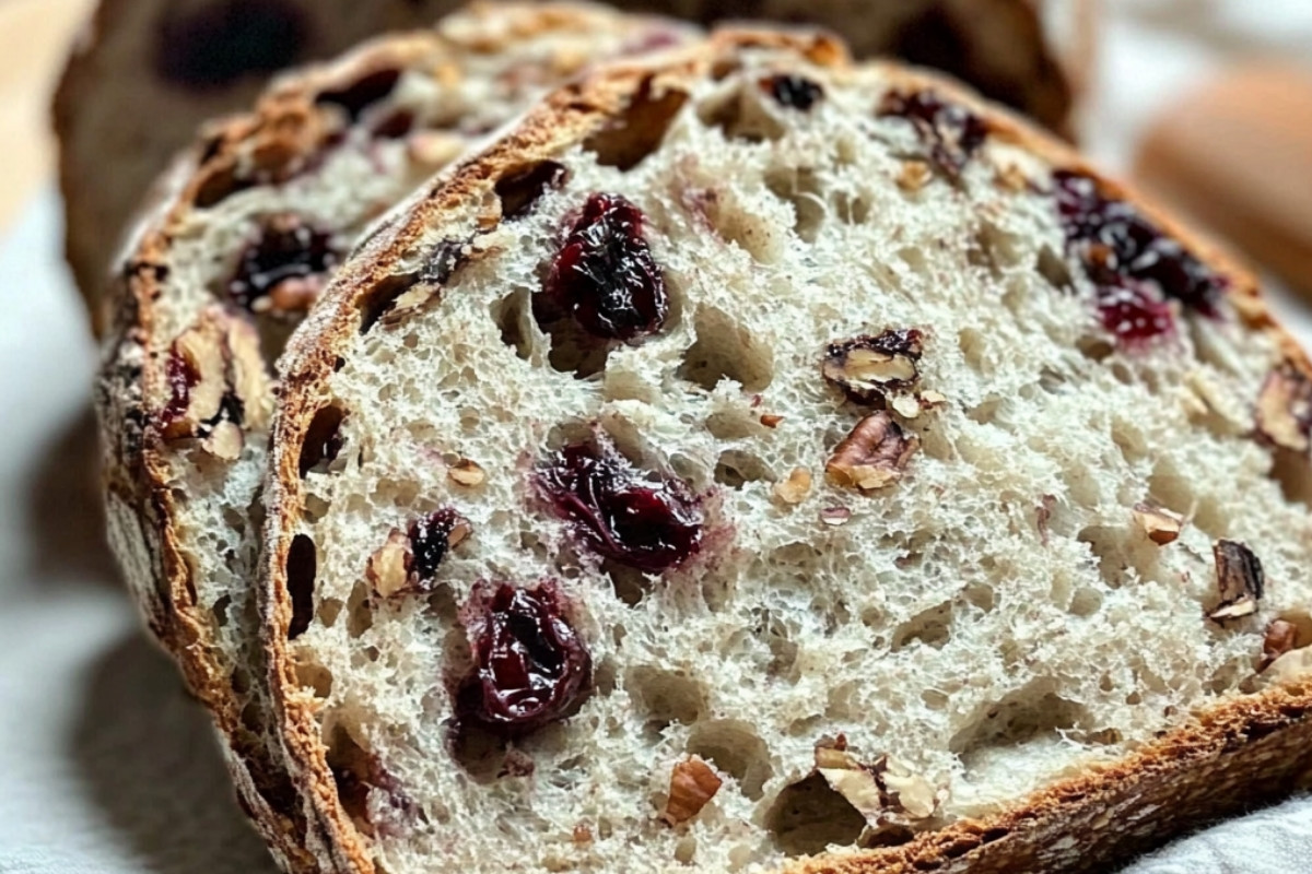 Freshly baked cranberry pecan artisan sourdough bread with a golden crust and studded with visible cranberries and pecans.