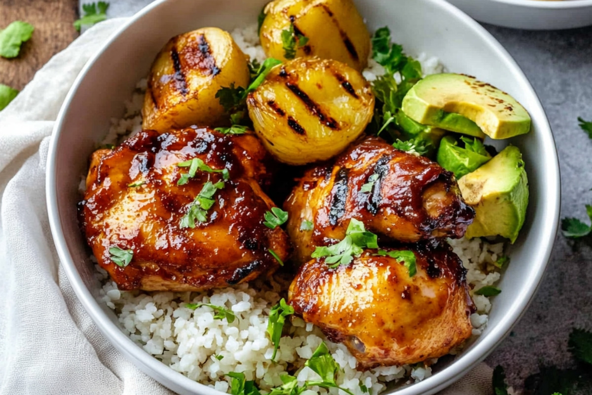 Grilled Hawaiian BBQ chicken topped with pineapple and green onions, served on a white plate with a side of rice.