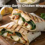 Cheesy garlic chicken wraps sliced open to reveal melted cheese, grilled chicken, and fresh greens