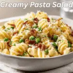 Creamy pasta salad garnished with bacon and parmesan on a clean, bright table setup