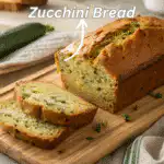 Sliced zucchini bread loaf on a wooden board with warm rustic styling