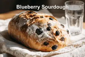 Golden blueberry sourdough bread on white napkin with warm background