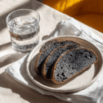 Plated activated carbon bread slices, elegantly placed with a glass of water on the side.