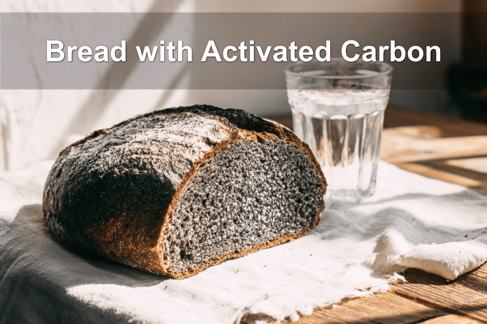 Freshly baked bread with activated carbon on a white napkin, glass of water beside it.