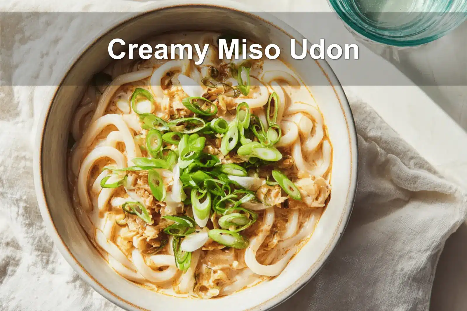 Bowl of Creamy Miso Udon with green onions in warm natural light