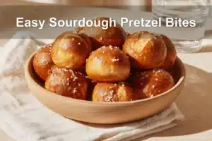 Golden-brown Easy Sourdough Pretzel Bites on white napkin with glass of water beside.