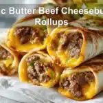 Garlic Butter Beef Cheeseburger Rollups on white napkin with melted cheese and pickles