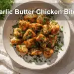 Garlic Butter Chicken Bites plated beautifully, garnished with parsley, and paired with a clear water glass