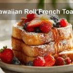 Hawaiian Roll French Toast plated with berries powdered sugar maple syrup on white cloth napkin