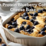 High Protein Blueberry Cottage Cheese Bake plated on white cloth with fresh blueberries and graham crumbs