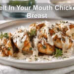 Melt In Your Mouth Chicken Breast plated with creamy white sauce and grated hard cheese warm lighting