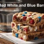 Red White and Blue M&M Cookie Bars - Perfect for Parties 4 Freshly baked Red White and Blue M&M Cookie Bars stacked on a white napkin with natural lighting.