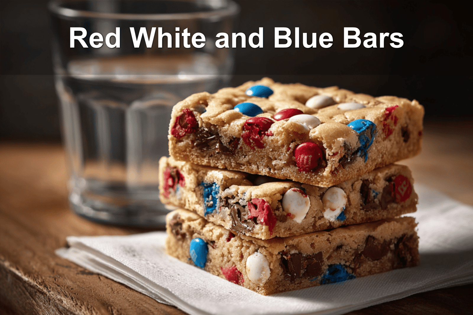 Freshly baked Red White and Blue M&M Cookie Bars stacked on a white napkin with natural lighting.