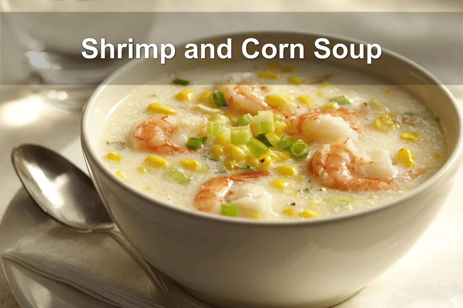 Shrimp and Corn Soup bowl on white napkin with shrimp corn creamy sauce and glass of water