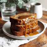 Glazed sourdough banana bread slices plated with a glass of water on the side.