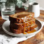 Glazed sourdough banana bread slices plated with a glass of water on the side.