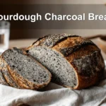 Sourdough Charcoal Bread on white napkin with glass of water in warm natural lighting