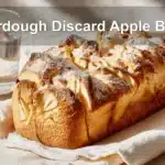 Sourdough Discard Apple Bread with cinnamon, apples, and powdered sugar, warm golden tones.