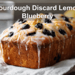 Sourdough Discard Lemon Blueberry Quick Bread beautifully presented with glass of water and warm tones