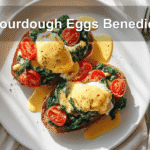 Sourdough Eggs Benedict Spinach Florentine on plate with hollandaise and tomato slices