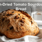 Sun-Dried Tomato Sourdough Bread on white napkin with water glass beside it.