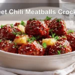 Sweet Chili Meatballs Crockpot in white dish with herbs, pineapple, and a glass of water