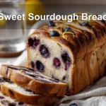 Sweet Sourdough Bread with golden crust, blueberries, and cheese on a white cloth napkin.
