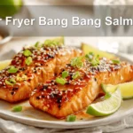 Air Fryer Bang Bang Salmon plated with sesame seeds lime wedges and green onions