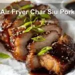 Air Fryer Char Siu Pork sliced glazed on white napkin with clear glass of water