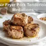 Air Fryer Pork Tenderloin Medallions: Easy Delicious Recipe 6 Air Fryer Pork Tenderloin Medallions plated on white napkin with glass of water and seasonings