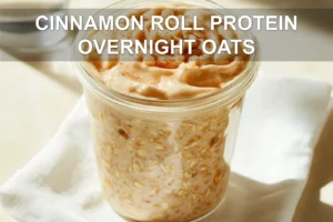CINNAMON ROLL PROTEIN OVERNIGHT OATS jar with cinnamon swirl on white napkin beside water