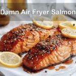 Damn Air Fryer Salmon plated with lemon slices honey soy glaze olive oil bottle beside glass