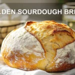 GOLDEN SOURDOUGH BREAD with open crumb and golden crust on white cloth beside glass of water