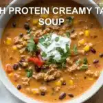 HIGH PROTEIN CREAMY TACO SOUP in bowl with herbs lime wedges and melted cheese