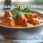 INDIAN BUTTER CHICKEN bowl on white napkin with warm sauce and glass of water
