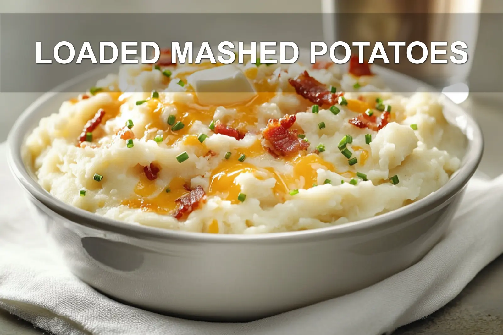 LOADED MASHED POTATOES topped with melted cheddar bacon chives butter and creamy white sauce on white cloth