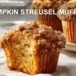 PUMPKIN STREUSEL MUFFINS on white cloth with clear glass of water warm light