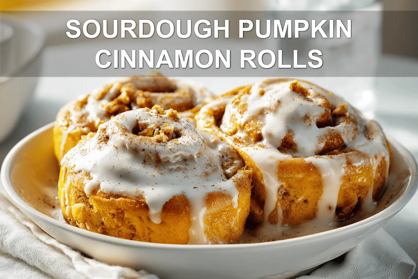 SOURDOUGH PUMPKIN CINNAMON ROLLS glazed rolls on white cloth with clear water glass