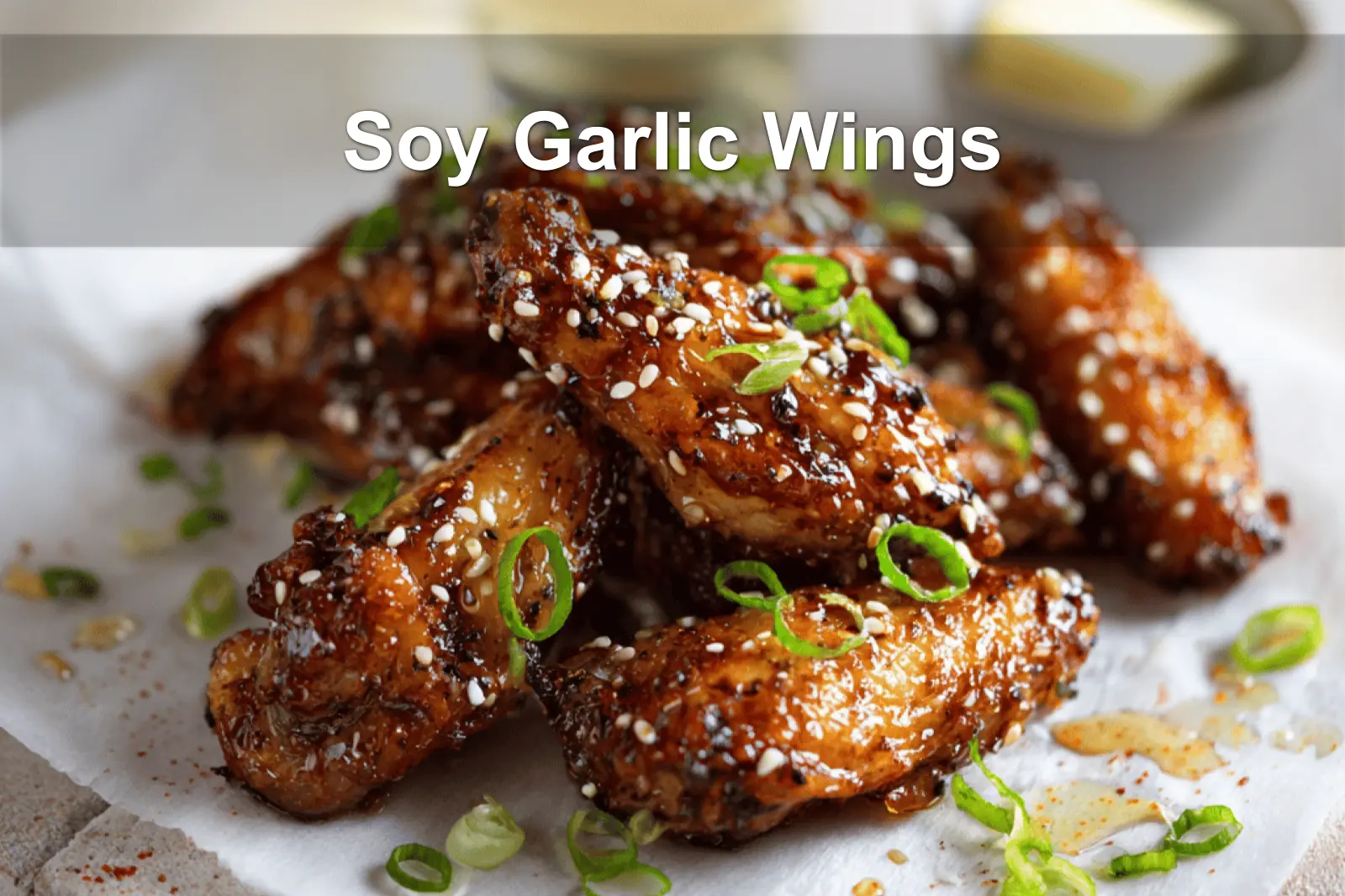 Soy Garlic Wings plated on white napkin with sesame seeds and green onions