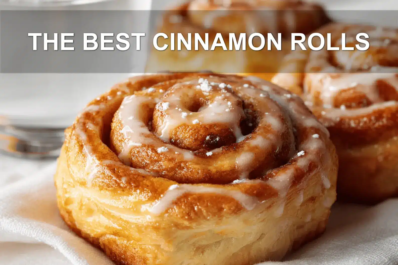 THE BEST CINNAMON ROLLS warm glazed pastries on white cloth with glass of water