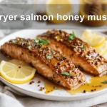 air fryer salmon honey mustard plated with lemon wedge and fresh herbs on white napkin