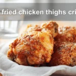 pan fried chicken thighs crispy golden skin on white cloth with simple glass of water