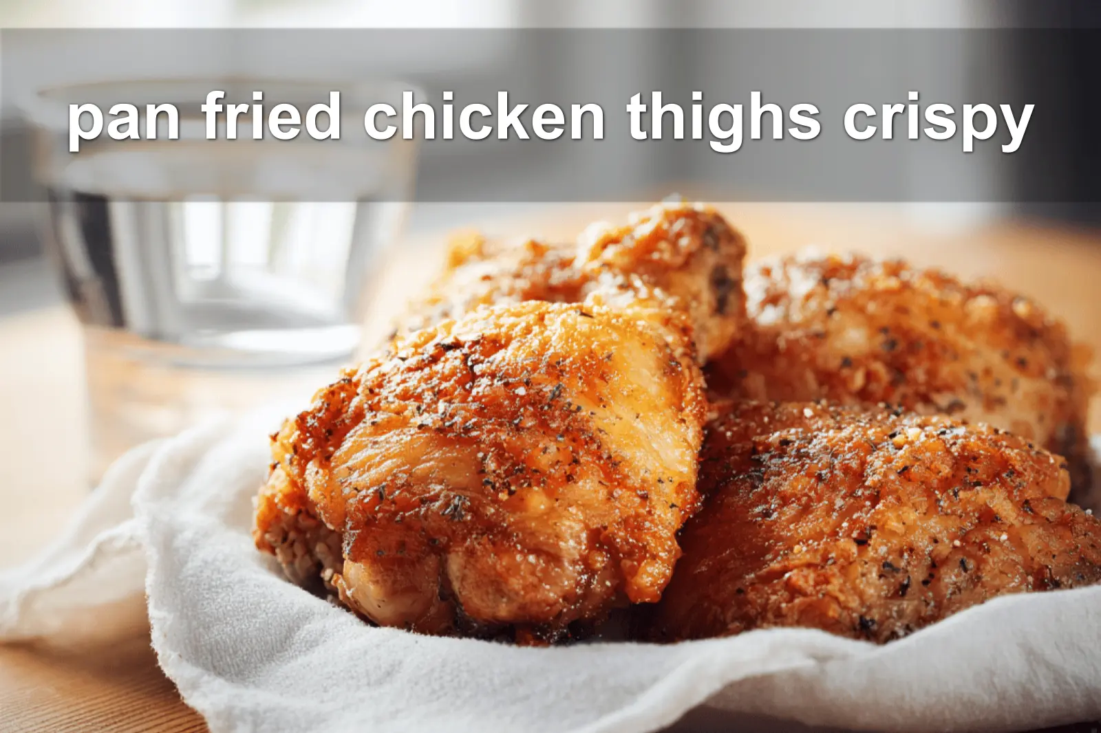 pan fried chicken thighs crispy golden skin on white cloth with simple glass of water