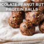 CHOCOLATE PEANUT BUTTER PROTEIN BALLS on white napkin with glass of water warm natural light