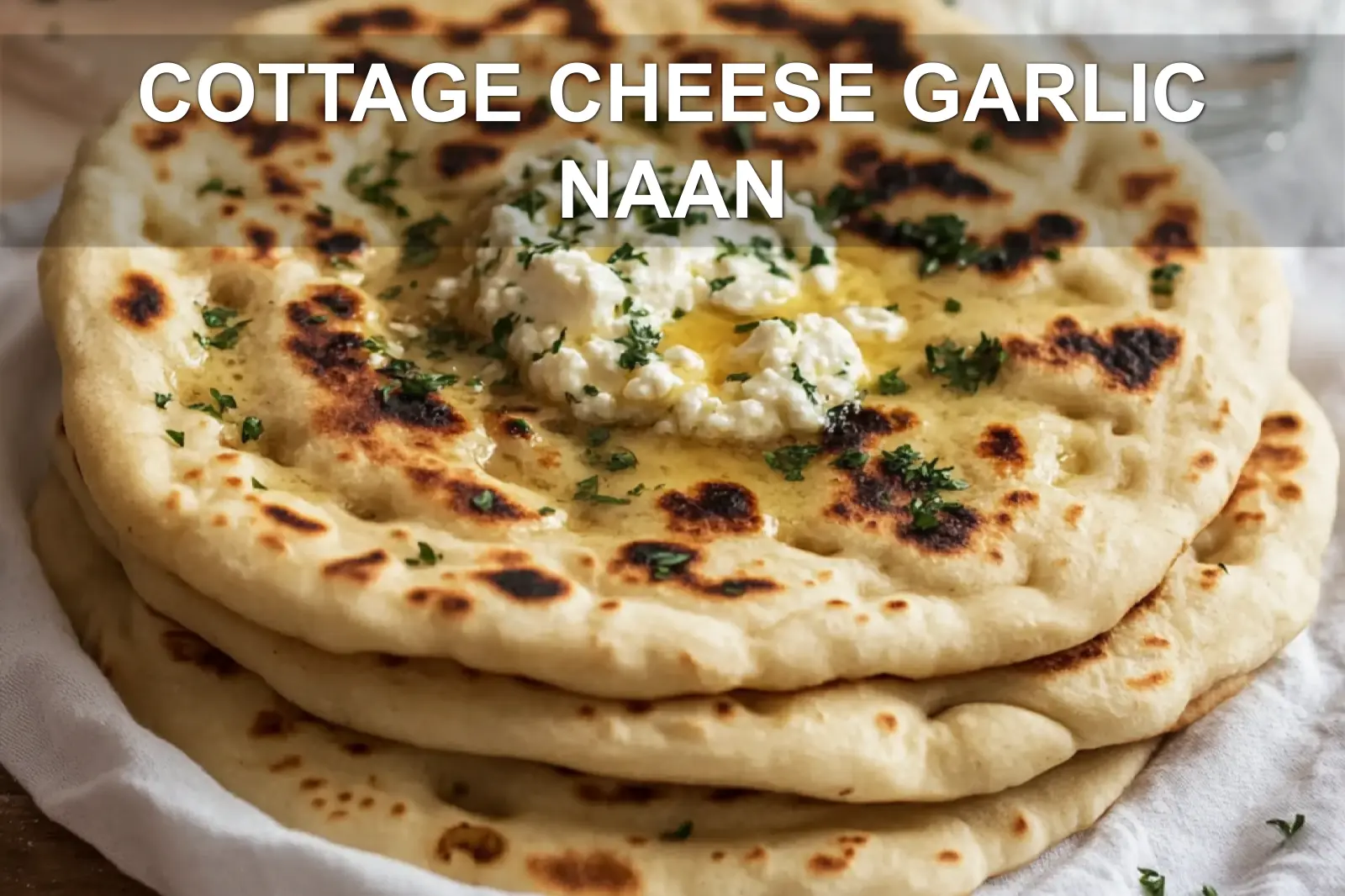 COTTAGE CHEESE GARLIC NAAN warm golden flatbreads on white napkin with a clear glass of water