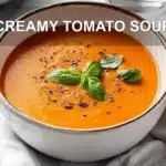 CREAMY TOMATO SOUP in a creamy bowl with basil garnish warm inviting main blog image