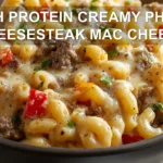 HIGH PROTEIN CREAMY PHILLY CHEESESTEAK MAC CHEESE plated bowl with melted cheese peppers and herbs